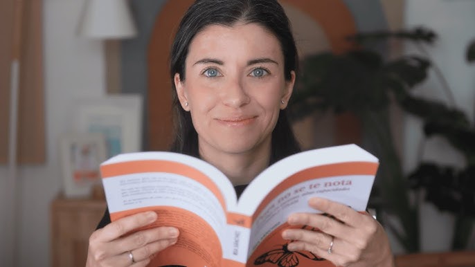 Mujer tiene el libro "Pues no se te nota" de Bea Sánchez abierto en sus manos y mira a la cámara sonriendo